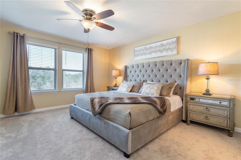 A bedroom features a tufted gray headboard, two nightstands with lamps, and a ceiling fan — 8931 ZURICH LANE, KISSIMMEE, FL