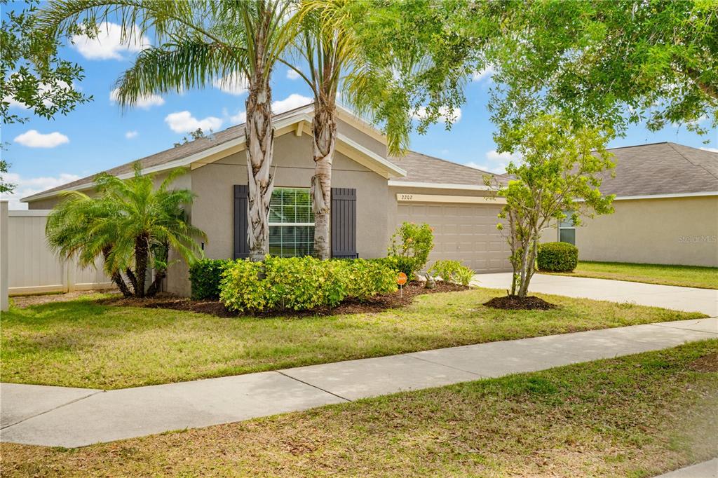 An elevated view of a single-story house with a concrete driveway and a backyard lake — 2202 4TH STREET SW, RUSKIN, FL