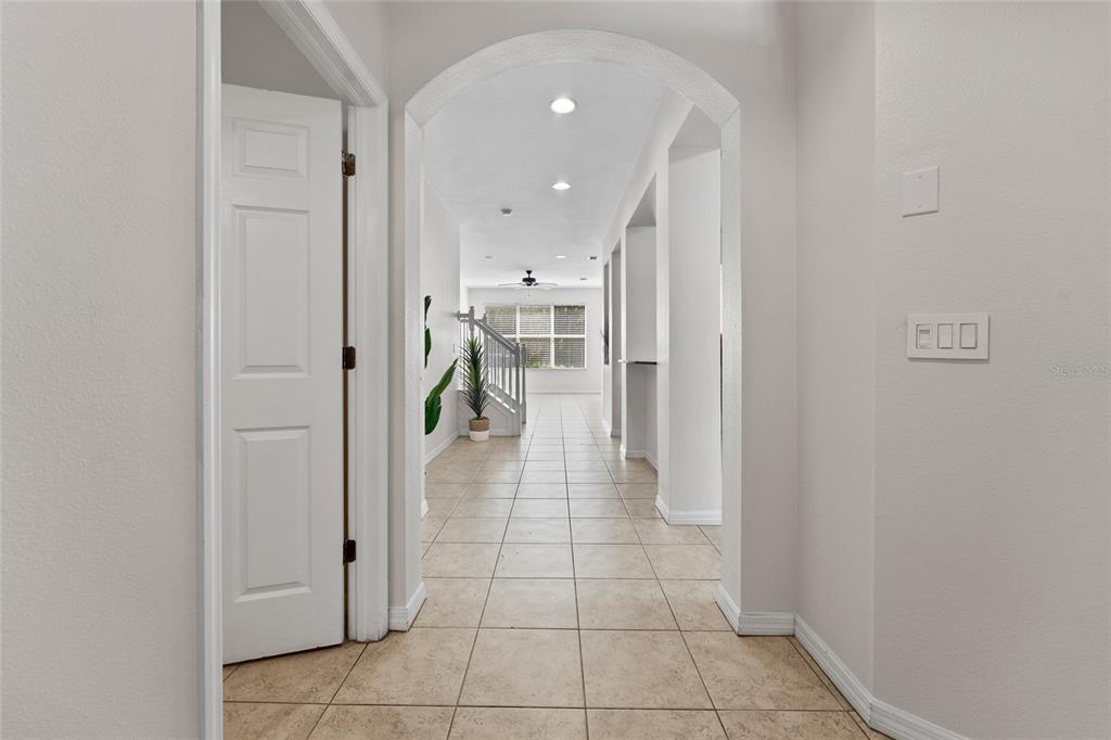 A tiled hallway leads through an arched doorway toward a staircase and a windowed room — 14055 WATERVILLE CIRCLE, TAMPA, FL