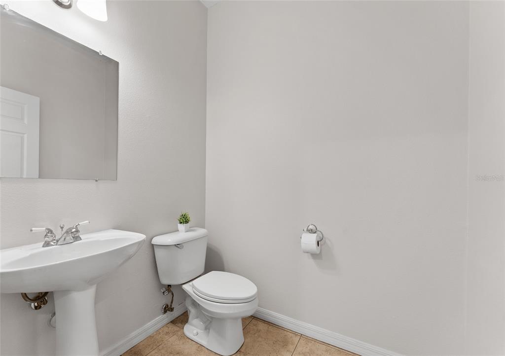 A small bathroom features a pedestal sink, a toilet, and a wall-mounted mirror — 14055 WATERVILLE CIRCLE, TAMPA, FL
