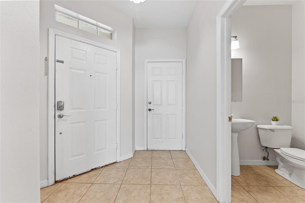 An entryway with tile flooring features a front door, a closet door, and a half bathroom — 14055 WATERVILLE CIRCLE, TAMPA, FL