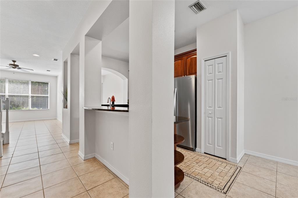 A view from a tiled kitchen area looking toward a living room with large windows — 14055 WATERVILLE CIRCLE, TAMPA, FL