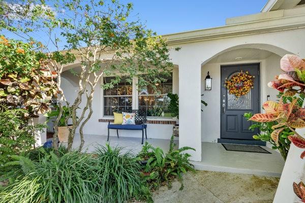 A covered front porch features a dark blue bench, a front door with a wreath, and landscaping — 14544 SW 76th St, Miami FL 33183, MIAMI, FL