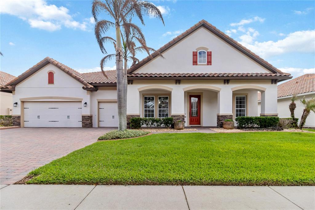 A single-story house with a tiled roof, red front door, and a three-car garage — 4257 ISLE VISTA AVENUE, BELLE ISLE, FL