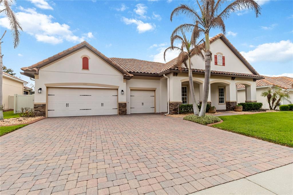 A single-story house with a paver driveway, three-car garage, and palm trees in the front — 4257 ISLE VISTA AVENUE, BELLE ISLE, FL