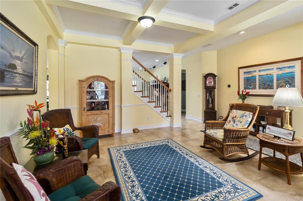 A living room with wicker chairs, a blue area rug, and a staircase — 4257 ISLE VISTA AVENUE, BELLE ISLE, FL