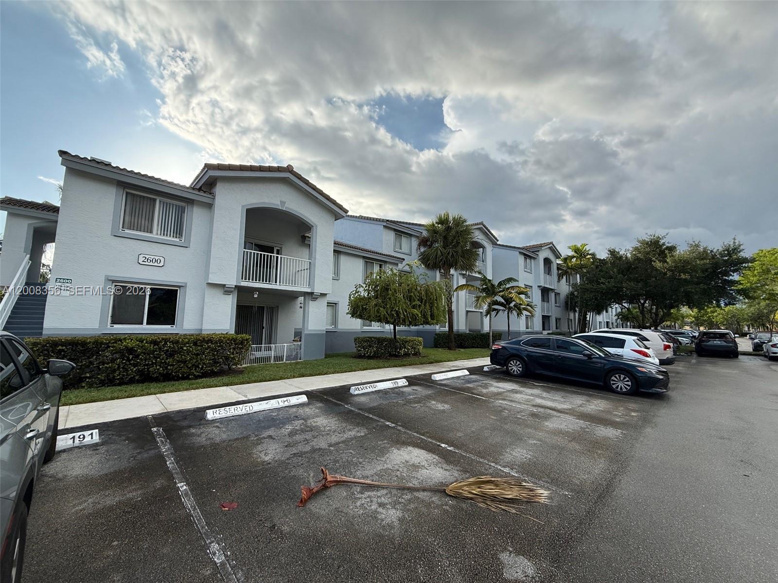 An exterior view of a multi-story apartment building with a parking lot in the foreground — 2600 S University Dr # 226, Davie FL 33328, DAVIE, FL