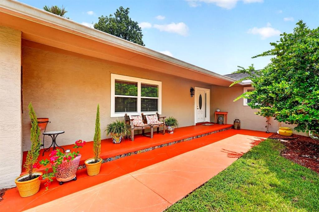 A house exterior features a bright orange concrete porch, a white front door, and landscaping — 20 TWIN RIVER DRIVE, ORMOND BEACH, FL