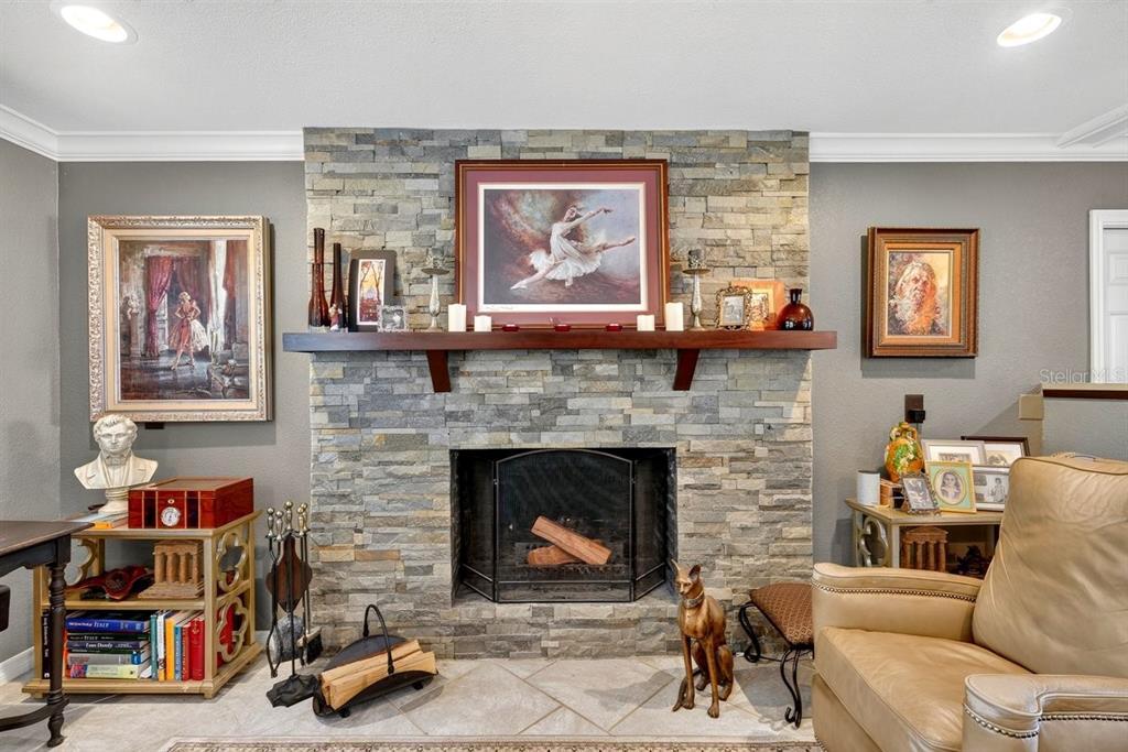 A stone fireplace with a wooden mantel serves as the focal point of this living room — 20 TWIN RIVER DRIVE, ORMOND BEACH, FL