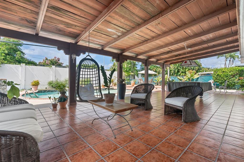 A covered outdoor patio features tile flooring, wicker furniture, and a view of a pool — Urb. Torrimar PASEO DE LA ALHAMBRA UNIT 1-16, GUAYNABO, PR