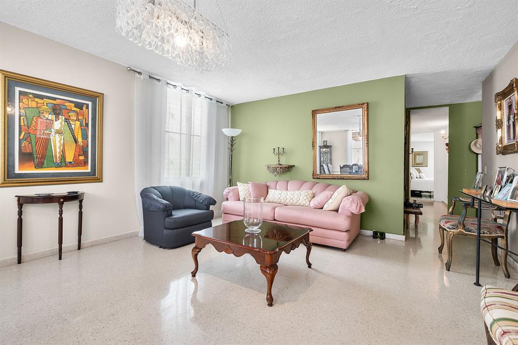 A living room features a pink sofa, a dark armchair, and a glass-topped coffee table — Urb. Torrimar PASEO DE LA ALHAMBRA UNIT 1-16, GUAYNABO, PR