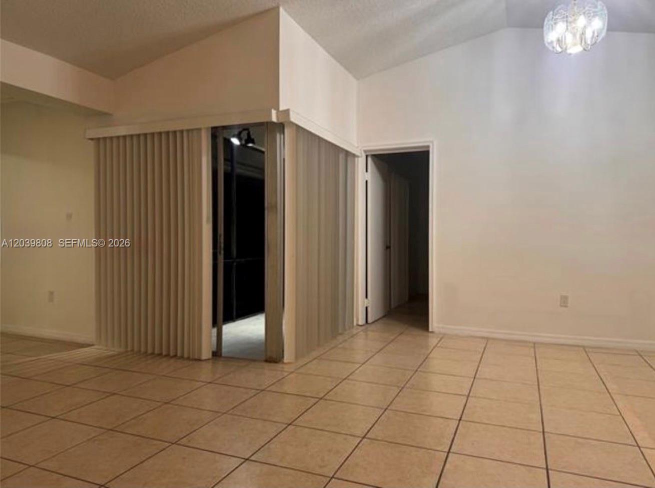 A room with tiled floors features a vertical blind partition and an open doorway — 819 NE 214th Ln # 1, Miami FL 33179, MIAMI, FL