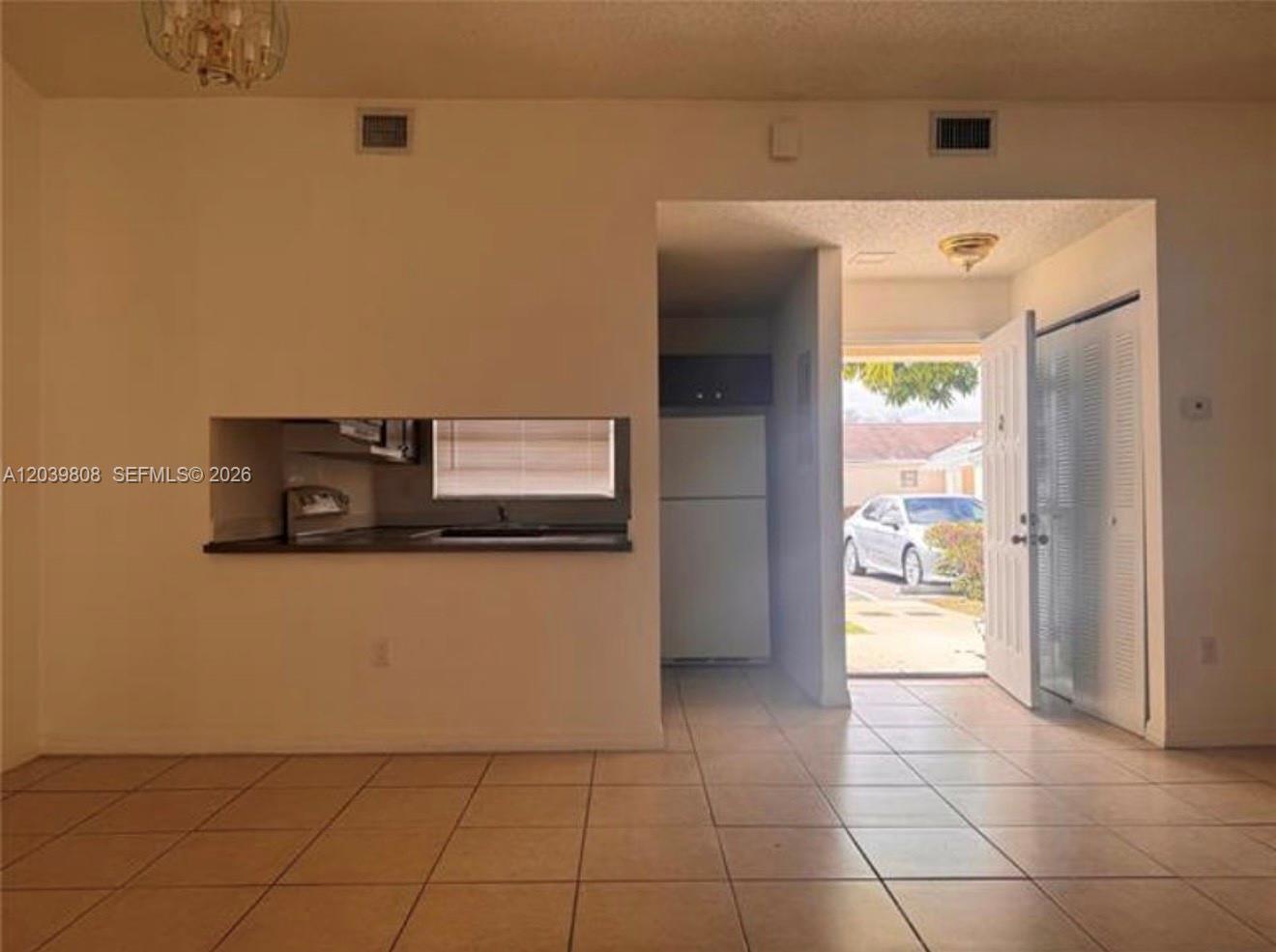 An interior view shows a tiled room with a kitchen pass-through and an open doorway — 819 NE 214th Ln # 1, Miami FL 33179, MIAMI, FL