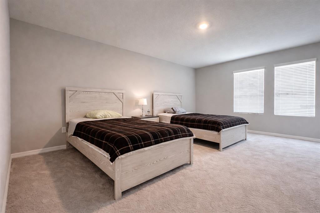 A bedroom features two beds with light wood frames and dark plaid bedding on carpet — 33546 DARLEY DALE TRAIL, WESLEY CHAPEL, FL