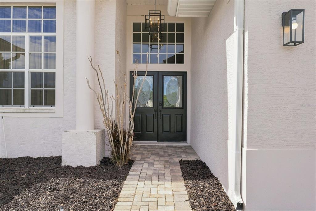 A paved walkway leads to a black double front door with a transom window above — 7258 ALOE DRIVE, SPRING HILL, FL