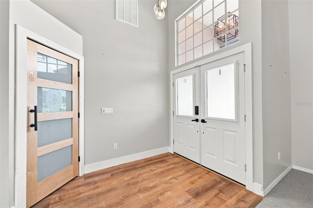 An entryway features wood-look flooring, a light wood door, and double white front doors — 7258 ALOE DRIVE, SPRING HILL, FL