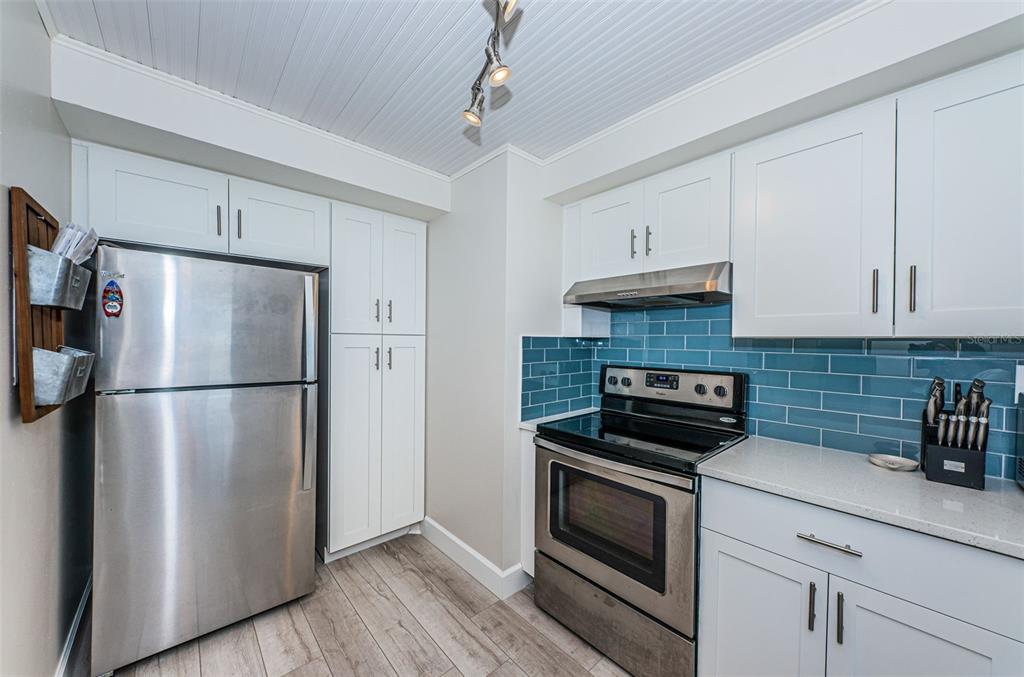 A kitchen features white cabinets, stainless steel appliances, and a blue subway tile backsplash — 6361 BAHIA DEL MAR BOULEVARD UNIT 503, ST PETERSBURG, FL