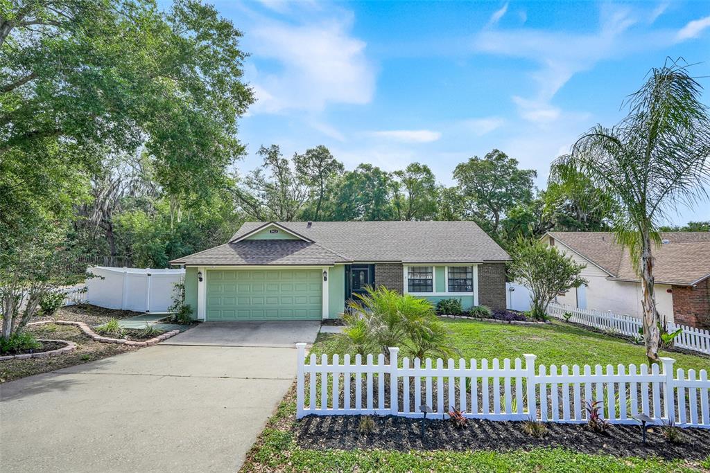 A single-story house with a green garage door and a white picket fence — 5933 GROVELINE DRIVE, ORLANDO, FL