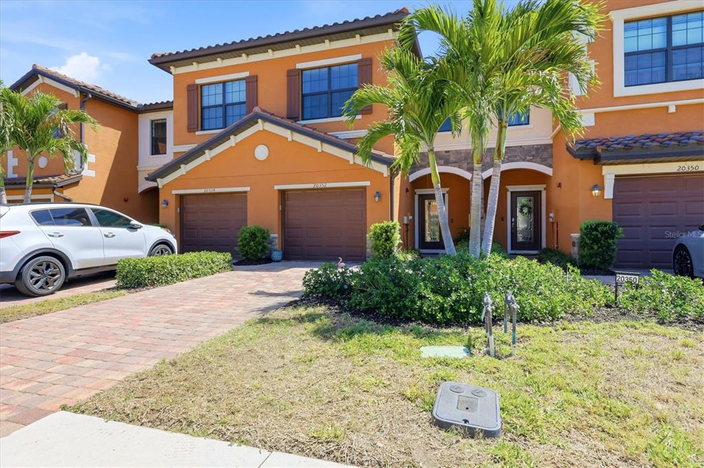 An aerial view shows a multi-unit residential building with orange stucco walls and tiled roofs — 20352 LAGENTE CIRCLE, VENICE, FL