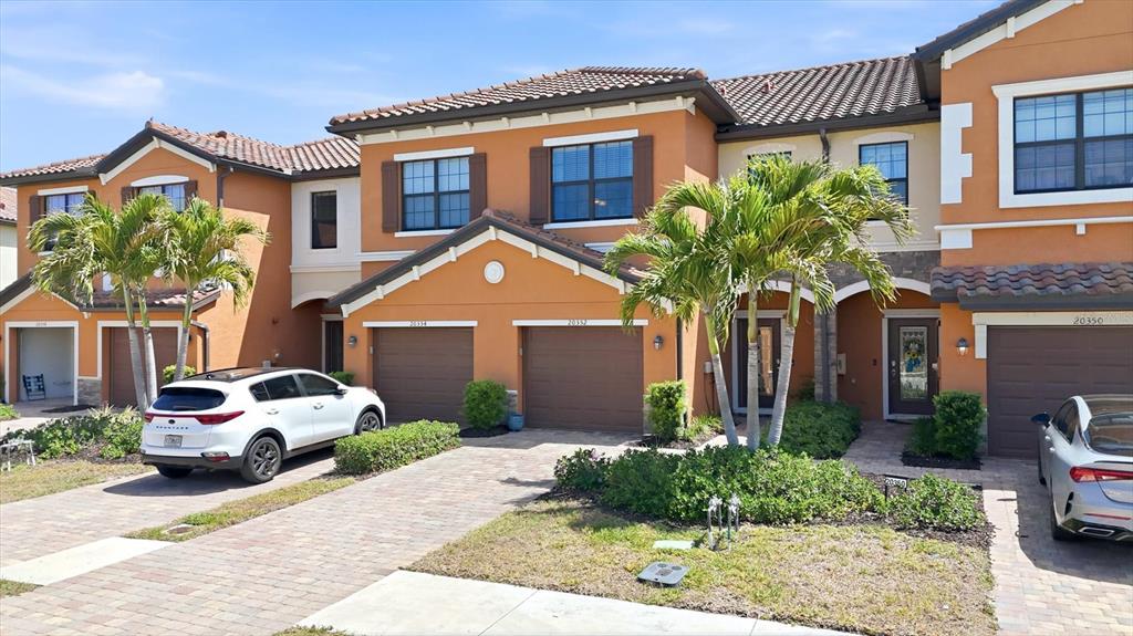 An aerial view shows a row of multi-story townhomes with terracotta roofs and driveways — 20352 LAGENTE CIRCLE, VENICE, FL