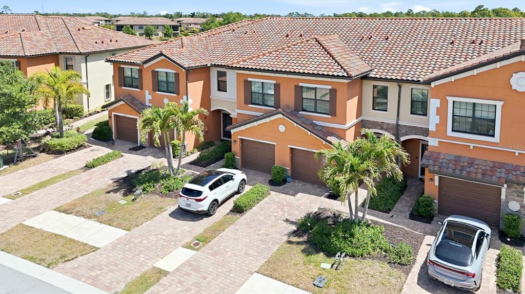 An aerial view shows multiple residential townhome buildings situated around a lake and green space — 20352 LAGENTE CIRCLE, VENICE, FL