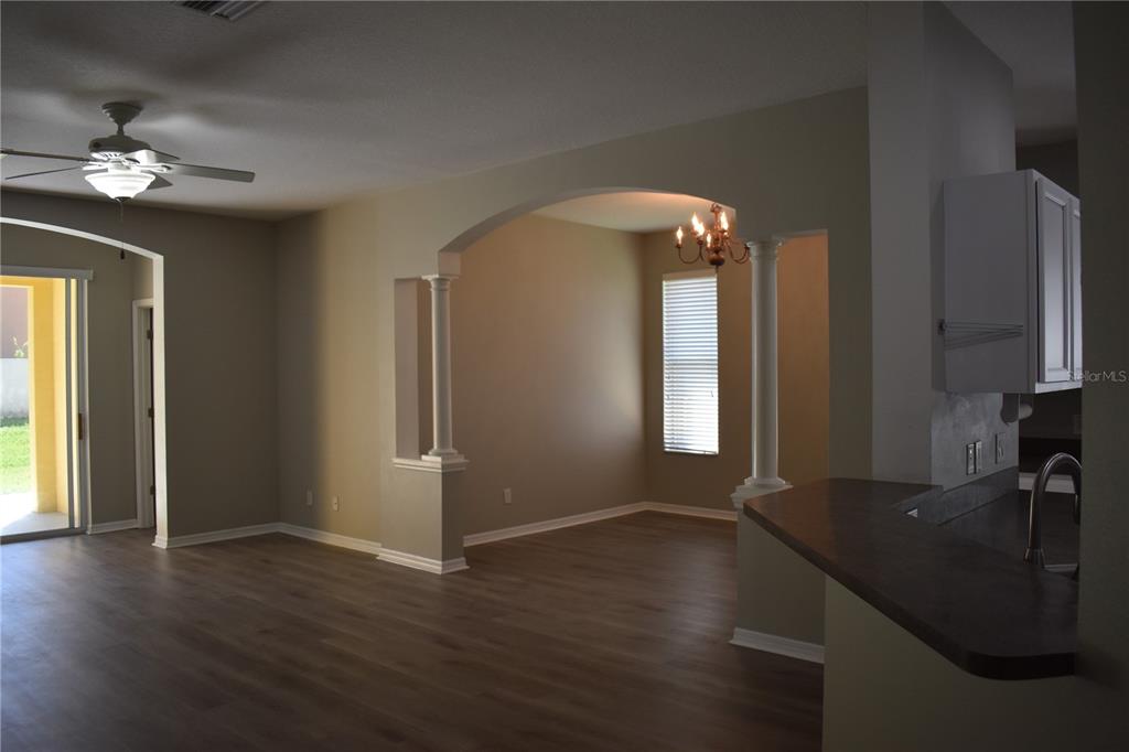 An open-concept living area features wood-look flooring, an arched entryway with columns, and a kitchen — 644 CHESNEY DRIVE, VALRICO, FL