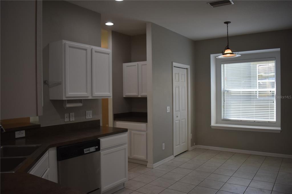 A kitchen with white cabinets, dark countertops, tile flooring, and a window with a pendant light — 644 CHESNEY DRIVE, VALRICO, FL
