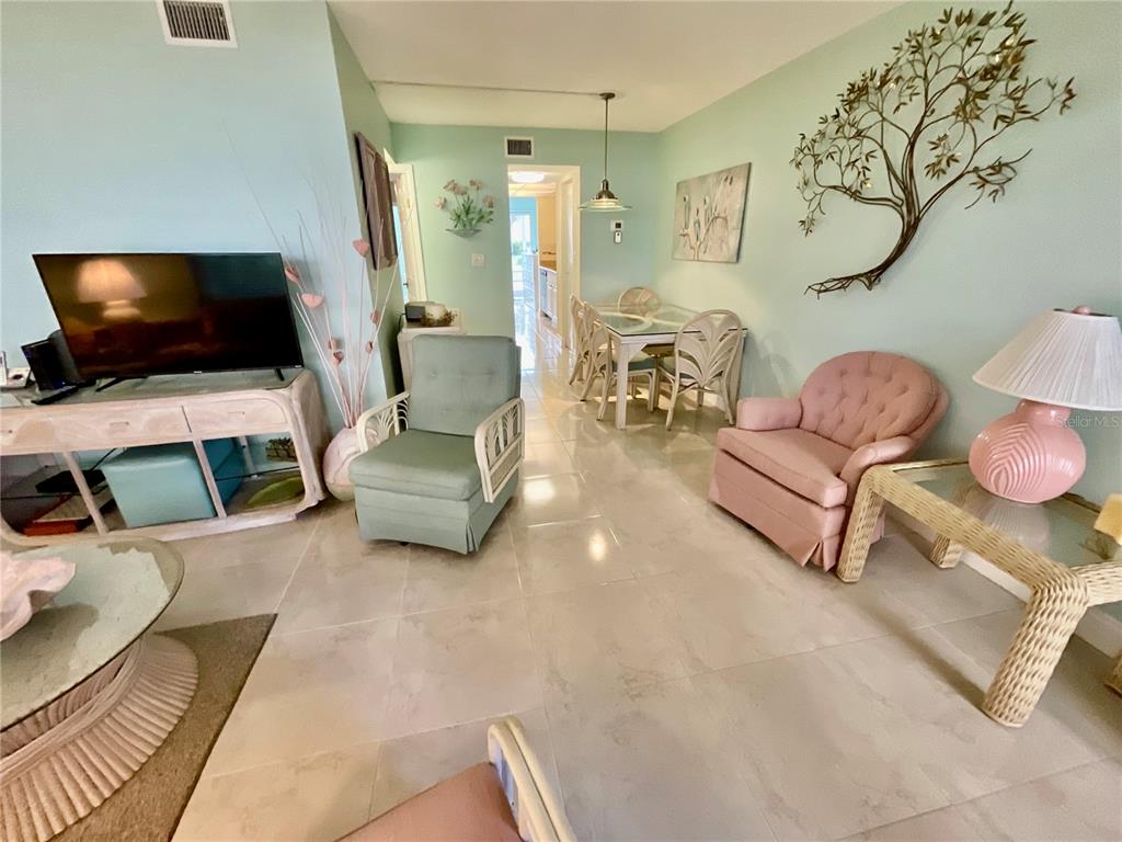 A living and dining area features light green walls, tile flooring, and pastel-colored furniture — 10034 64TH AVENUE N UNIT 11, ST PETERSBURG, FL