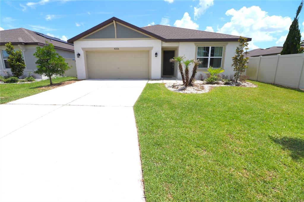 A single-story house with a beige stucco exterior, a two-car garage, and a front lawn — 4006 CAPRI COAST DRIVE, PLANT CITY, FL