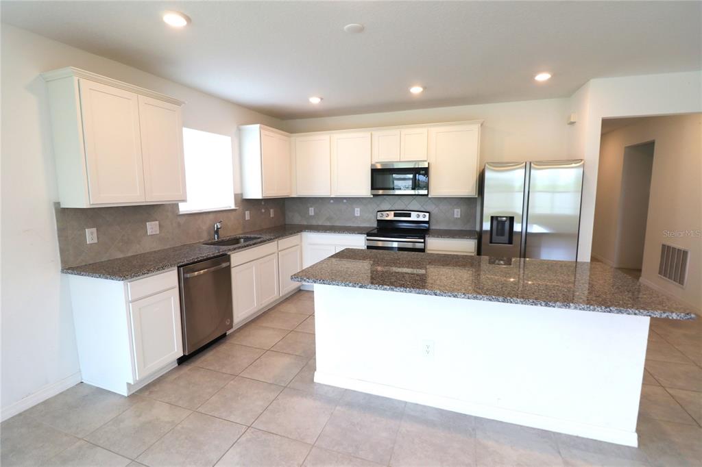 A kitchen features white cabinets, granite countertops, stainless steel appliances, and a central island — 4006 CAPRI COAST DRIVE, PLANT CITY, FL