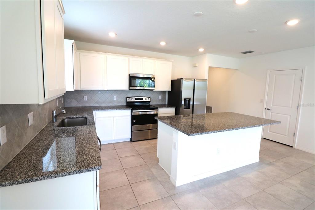 A kitchen with white cabinets, granite countertops, stainless steel appliances, and a central island — 4006 CAPRI COAST DRIVE, PLANT CITY, FL
