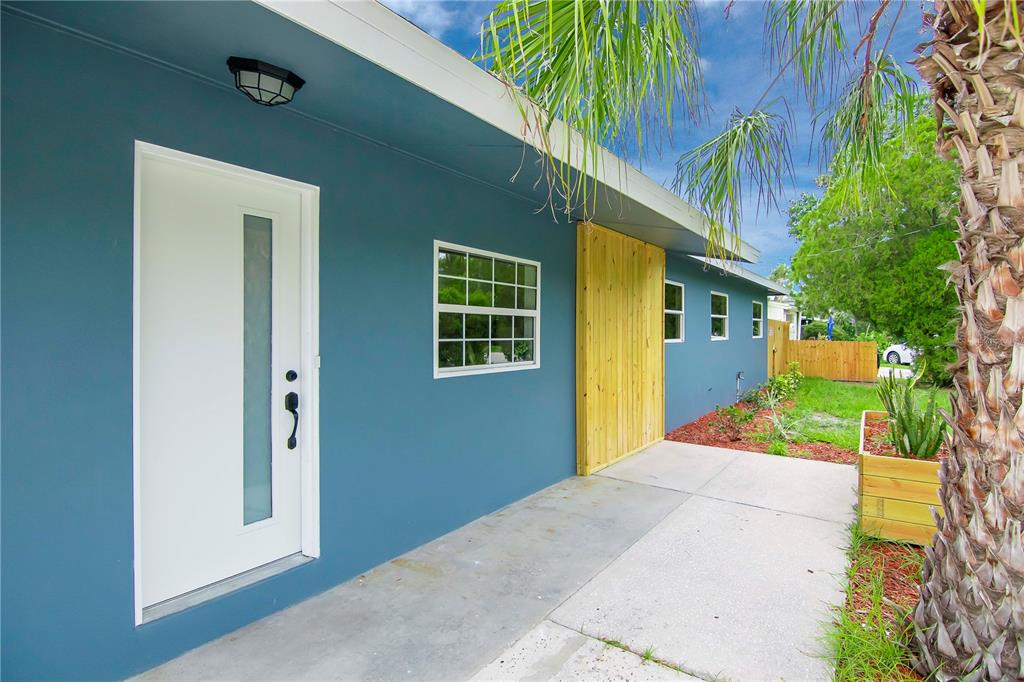 A blue exterior wall features a white modern door, a window, and wood paneling — 3708 W TYSON AVENUE, TAMPA, FL