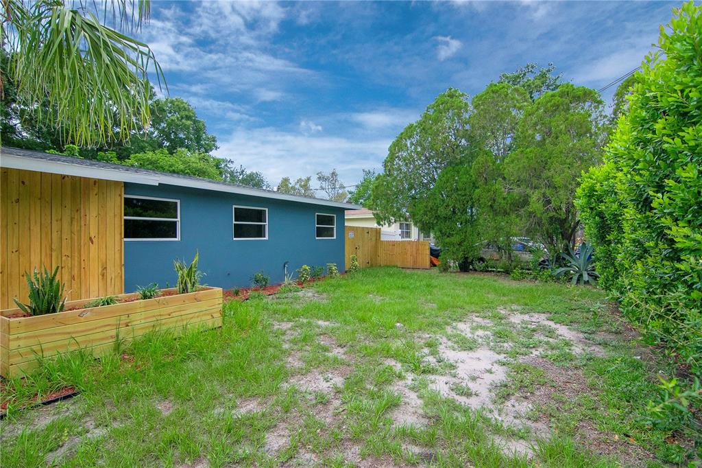 A blue house exterior with a wooden planter box and a grassy backyard — 3708 W TYSON AVENUE, TAMPA, FL
