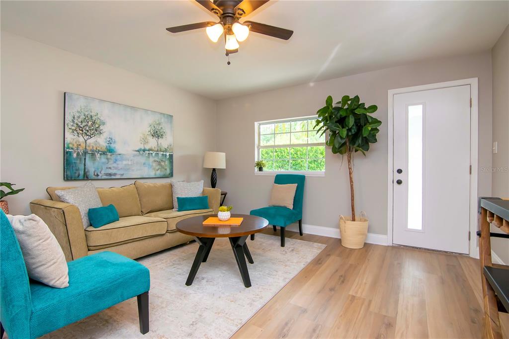 A living room features a tan sofa, two teal chairs, a coffee table, and wood flooring — 3708 W TYSON AVENUE, TAMPA, FL