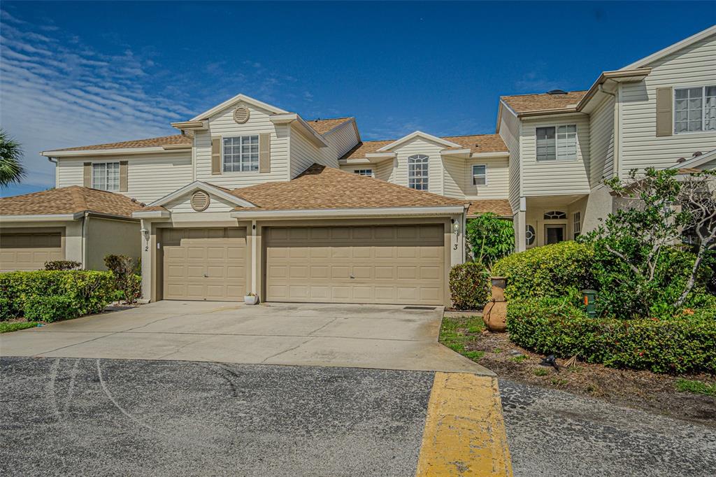 A two-story townhouse exterior features tan siding, a shingled roof, and two garage doors — 6400 46TH AVENUE N UNIT 3, KENNETH CITY, FL