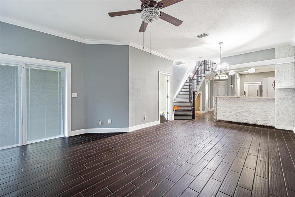 An open-concept living area features dark wood-look tile flooring, gray walls, and a staircase — 6400 46TH AVENUE N UNIT 3, KENNETH CITY, FL