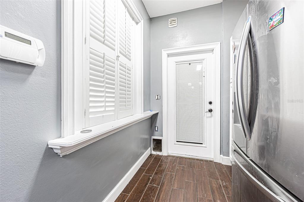 A kitchen area features a window with shutters, a glass-paneled door, and wood-look tile flooring — 6400 46TH AVENUE N UNIT 3, KENNETH CITY, FL