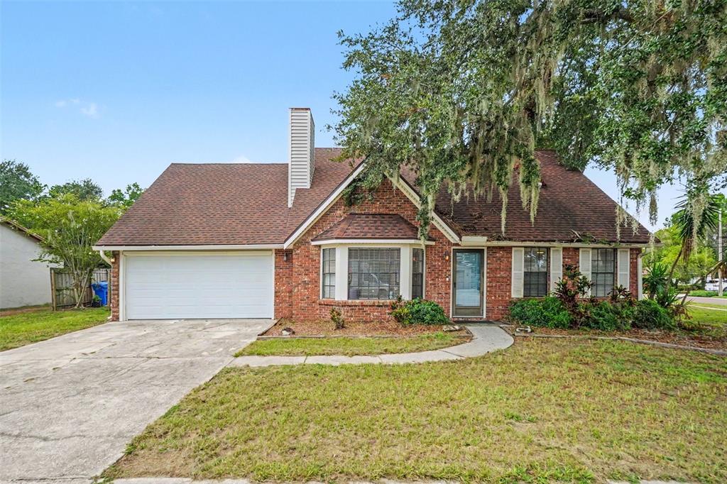 A single-story brick house with a front-facing garage, a bay window, and a large tree — 736 SANDY CREEK DRIVE, BRANDON, FL