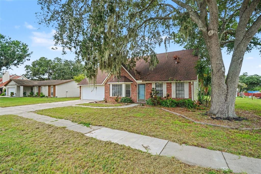 A single-story brick and siding house with a two-car garage and a large oak tree — 736 SANDY CREEK DRIVE, BRANDON, FL