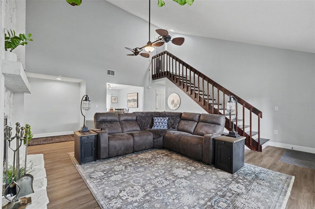 A living room features a sectional sofa, a large area rug, and a wooden staircase — 736 SANDY CREEK DRIVE, BRANDON, FL