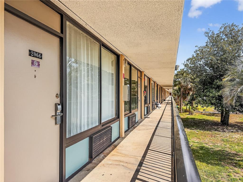 An exterior walkway leads past a row of hotel-style doors and windows under a roof — 7900 S ORANGE BLOSSOM TRAIL UNIT 2066, ORLANDO, FL