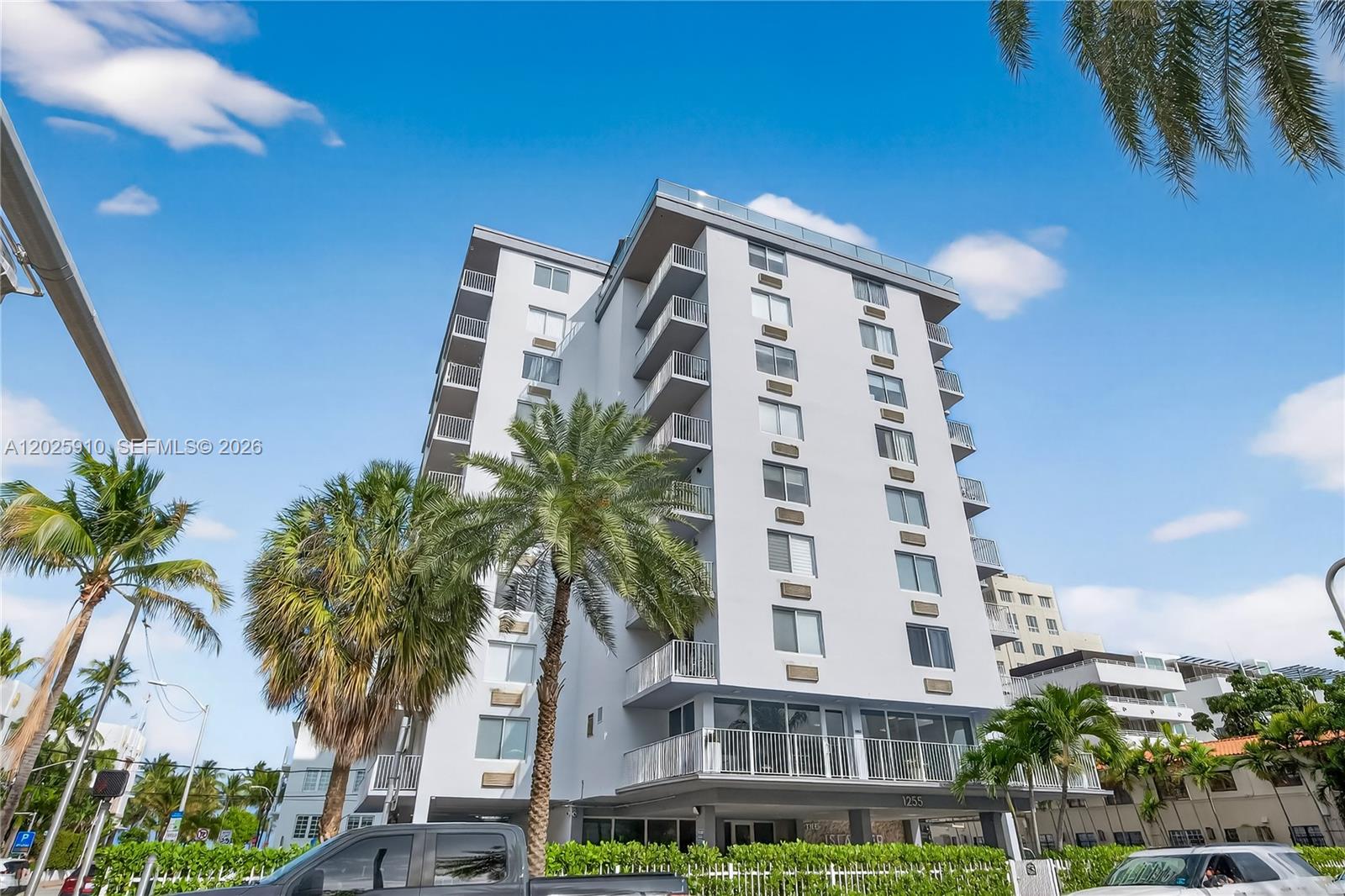 A multi-story white apartment building features balconies and palm trees under a blue sky — 1255 Collins Ave # 504, Miami Beach FL 33139, MIAMI BEACH, FL