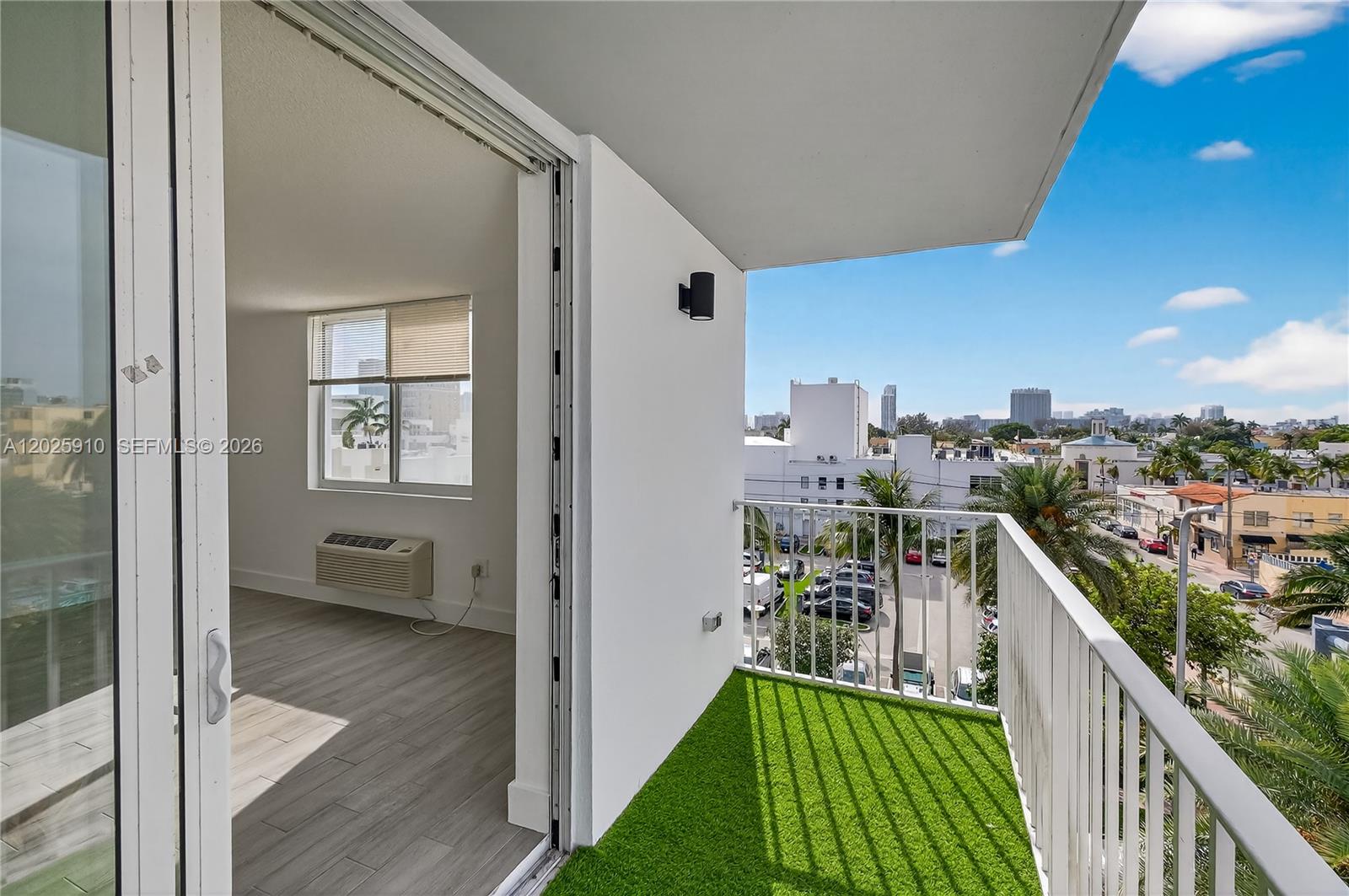 A balcony with artificial turf overlooks a parking lot and city buildings — 1255 Collins Ave # 504, Miami Beach FL 33139, MIAMI BEACH, FL