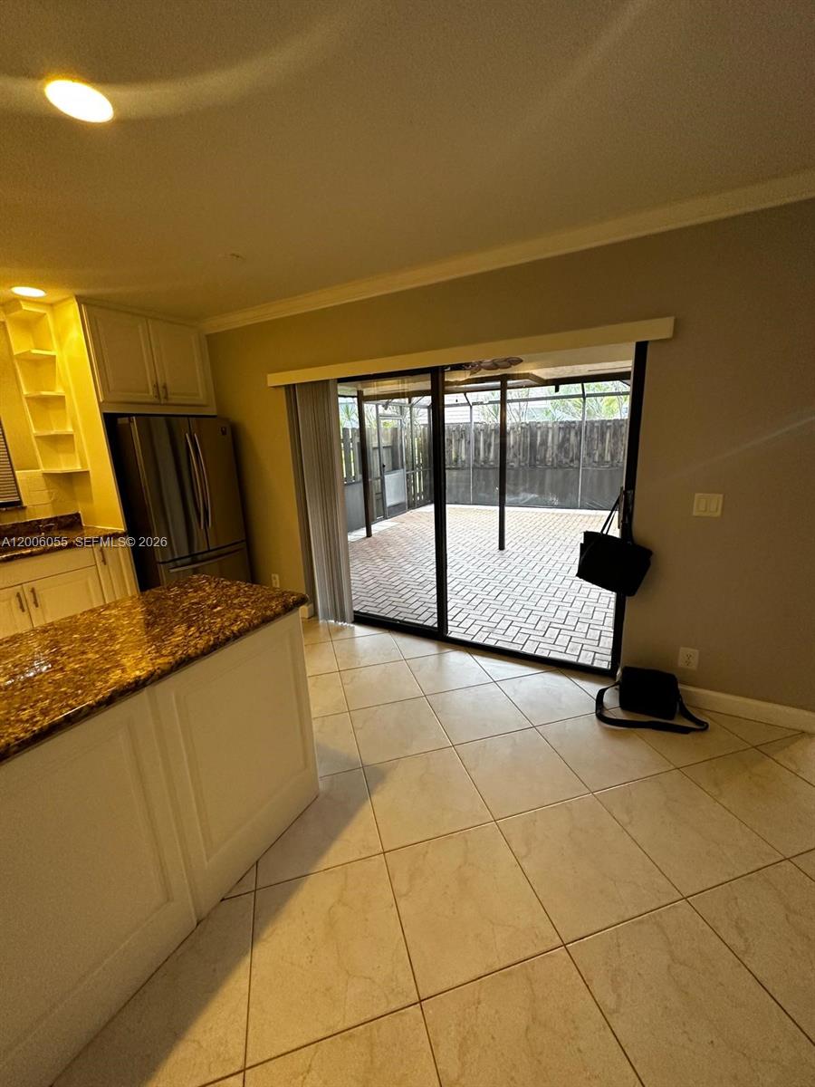 A kitchen with granite countertops overlooks a screened-in patio with brick pavers — 7671 W Courtyard Run W, Boca Raton FL 33433, BOCA RATON, FL
