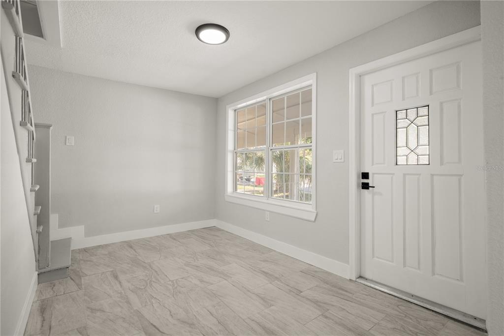An entryway with light gray walls, tile flooring, a staircase, and a white front door — 309 BATH STREET, TARPON SPRINGS, FL