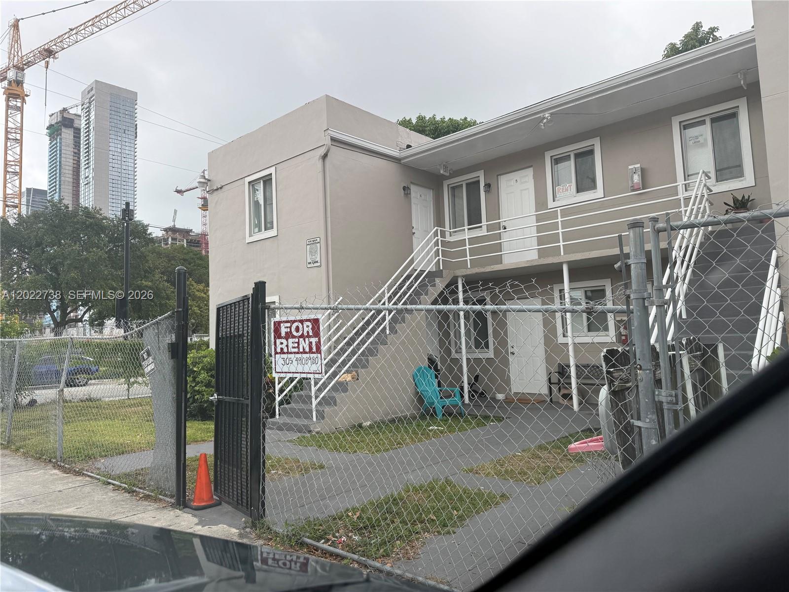 A two-story apartment building with a chain-link fence and a for rent sign — MIAMI, FL