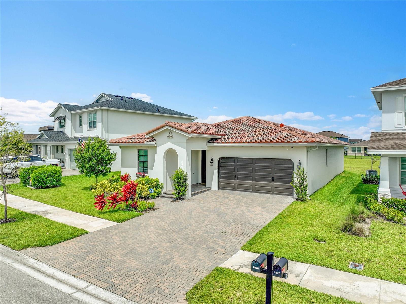 A single-story house with a tiled roof, brick driveway, and a two-car garage — 1878 Wandering Willow Way, FL 33470, FL