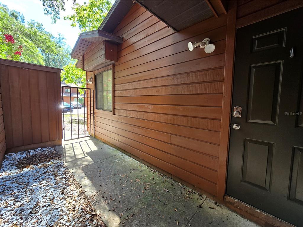 A wooden exterior wall with a door, a window, and a small concrete patio area — 842 SW 55TH TERRACE, GAINESVILLE, FL