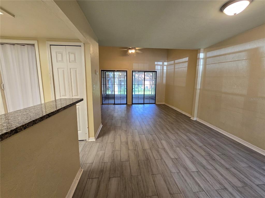 An interior view showing a living area with wood-look tile flooring and sliding glass doors — 842 SW 55TH TERRACE, GAINESVILLE, FL