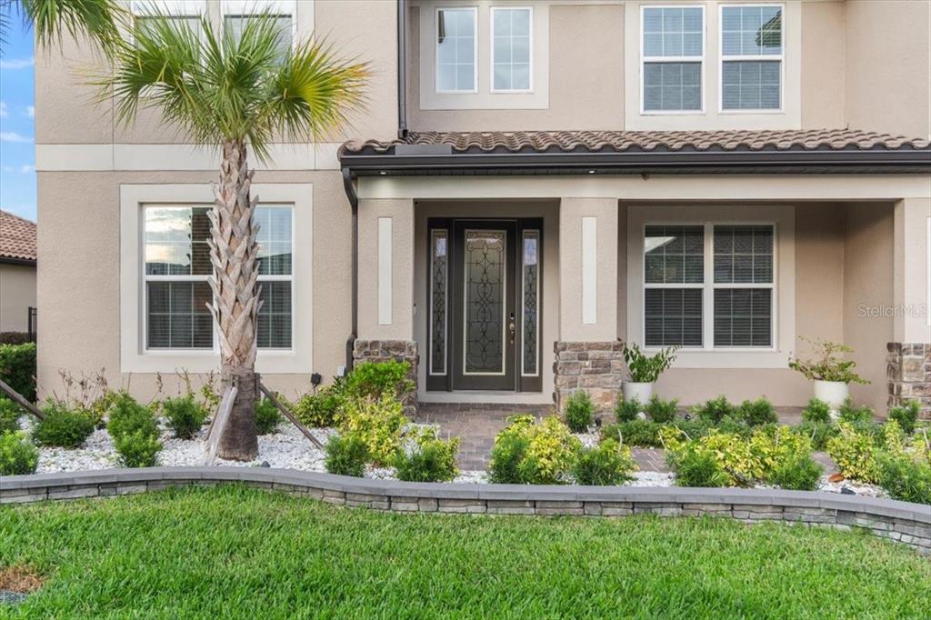 A two-story house exterior features a covered entryway, stone accents, and a palm tree — 33239 KATELAND DRIVE, WESLEY CHAPEL, FL
